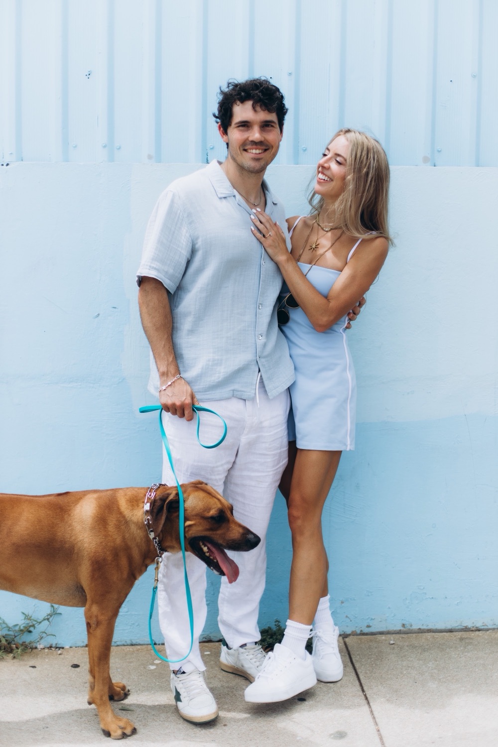Hunter, Mary, and their dog against a pale blue wall