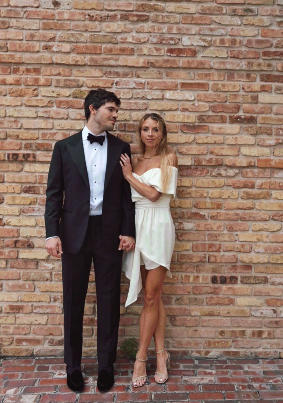Hunter and Mary holding hands in their evening clothes against a brick wall