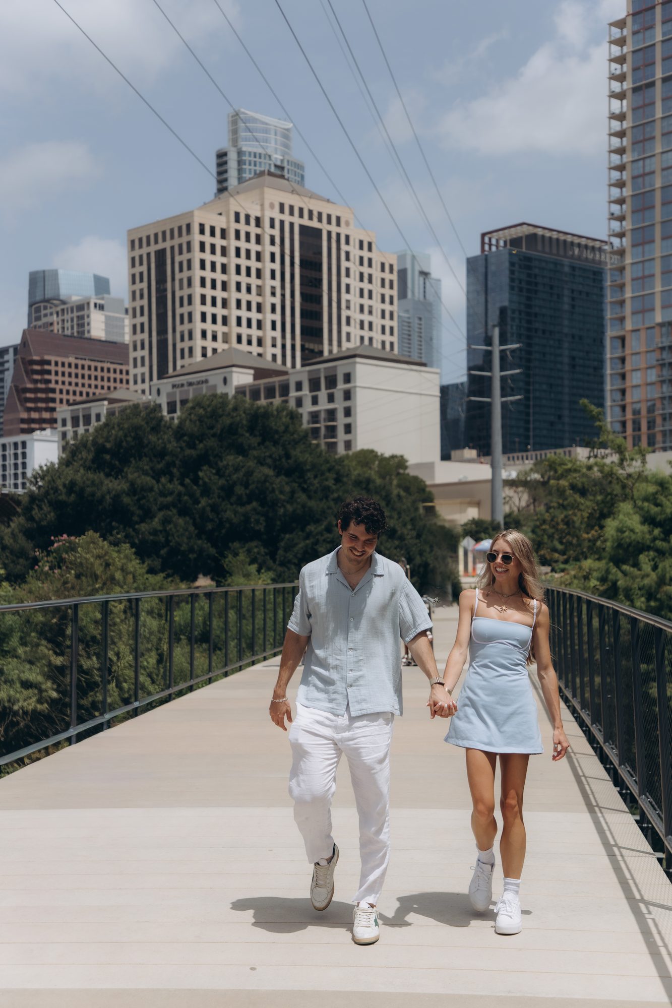 Hunter and Mary walking hand in hand with the Austin skyline behind them